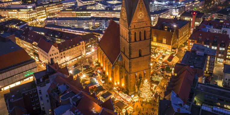 Blick aus größerer Höhe auf den beleuchteten Weihnachtsmarkt rund um die Marktkirche in Hannover.